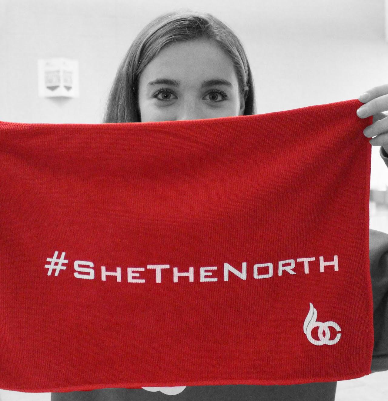 Black and white image of student holding red "She the North" flag