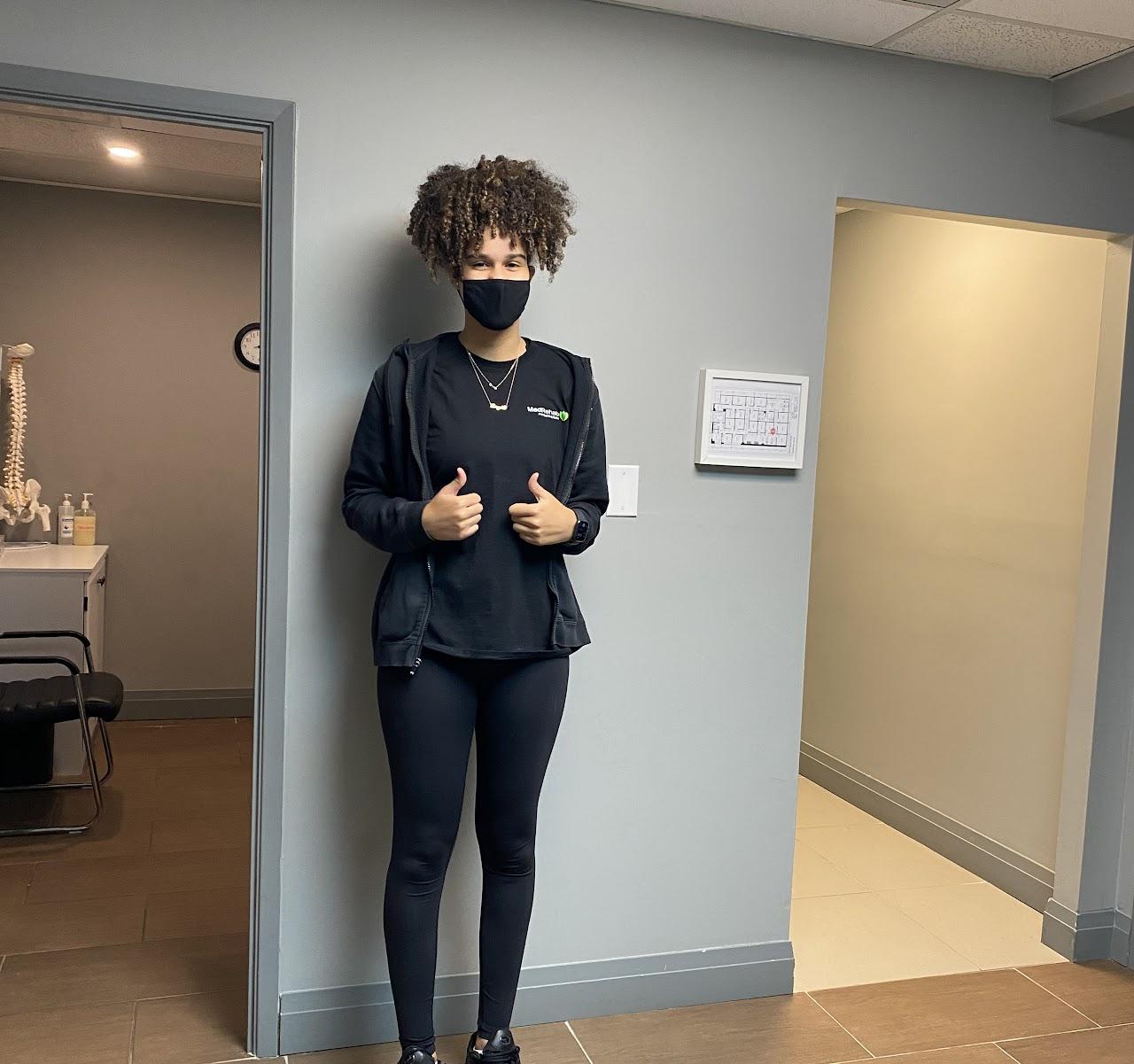 student stands outside office giving thumbs up