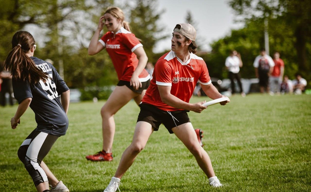 student in red uniform is about to throw a frisbee on a field