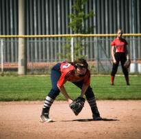 student in red Colts uniform is bent down ready wearing a softball globe