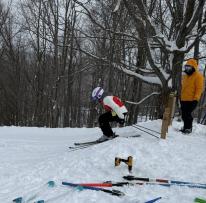 student perpares to go downhill on skis, skis lay on ground nearby