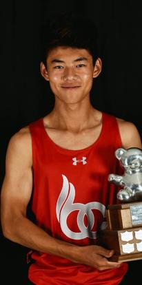 Student in red colts uniform holds large trophy smiling