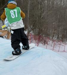 student wearing number 87 about to go off a jump on a snowboard