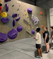 rock climbing team member climbing with others watching