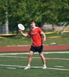 student throwing frisbee on pitch