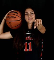 student holding basketball pointing at camera