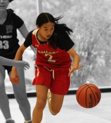 student playing basketball against greyed out opponents