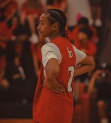 student in basketball uniform standing on court