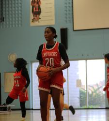 student in basketball uniform holding basketball on court