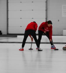 students sweeping on curling rink