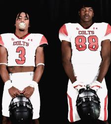 two football players holding their helmets