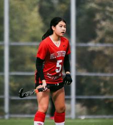 student standing on field hockey pitch