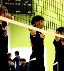 three student volleyball players standing near net