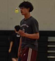 student tossing badminton birdie